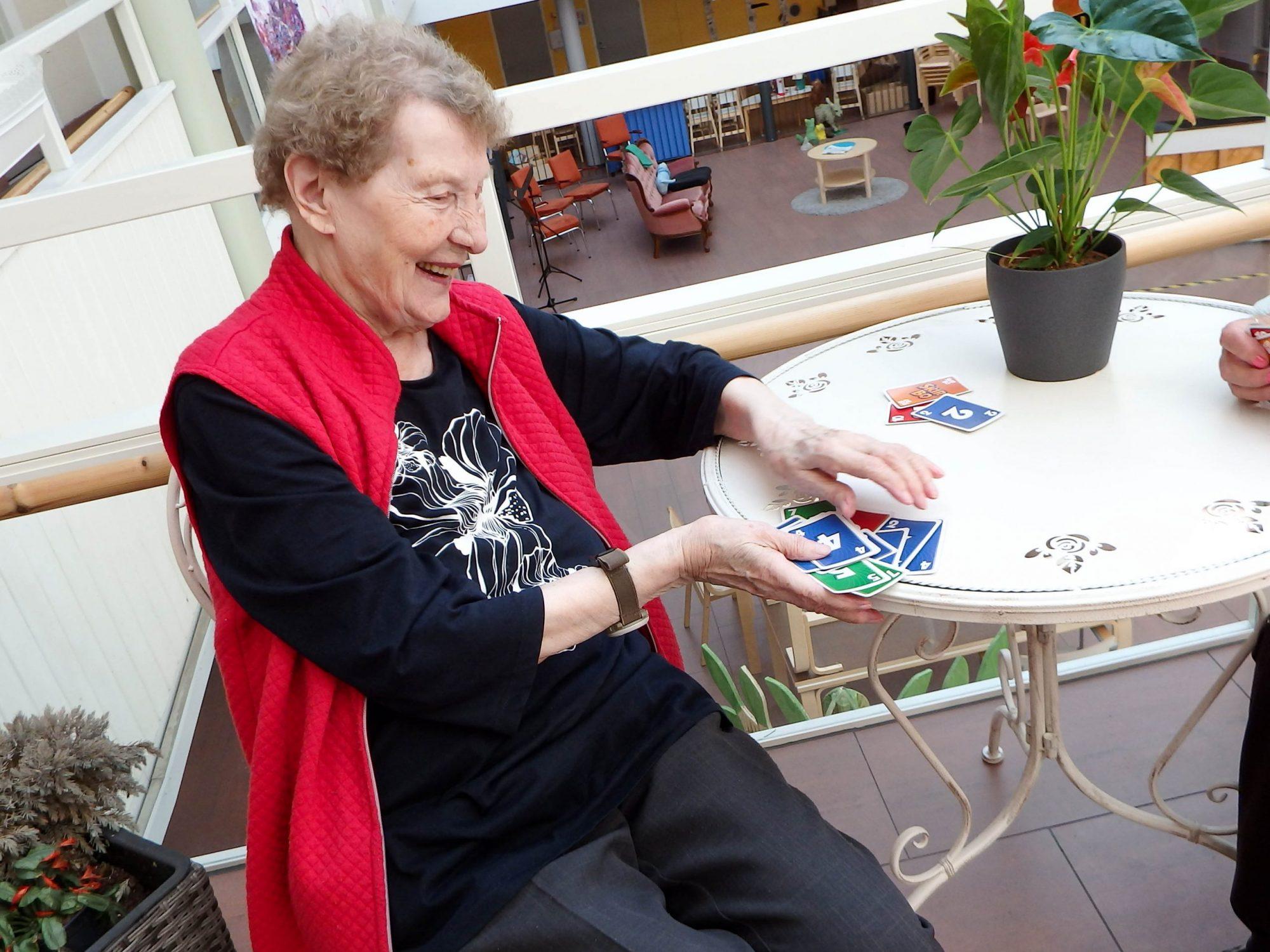 Raija pöydän ääressä sekoittamassa skipbo-kortteja