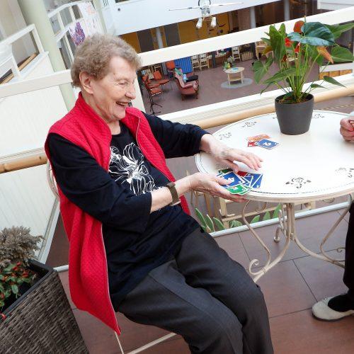 Raija pöydän ääressä sekoittamassa skipbo-kortteja